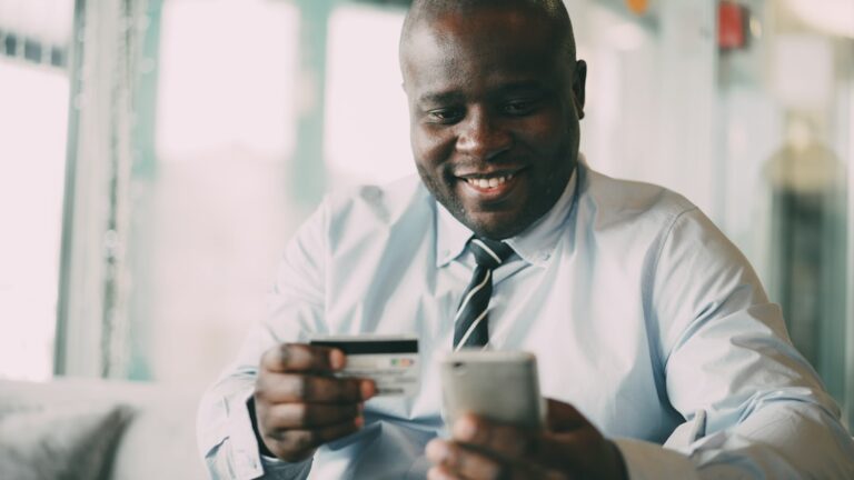 Homem Sorrindo Enquanto Segura Cartao De Credito E Telefone zh6Qq0w_5GU