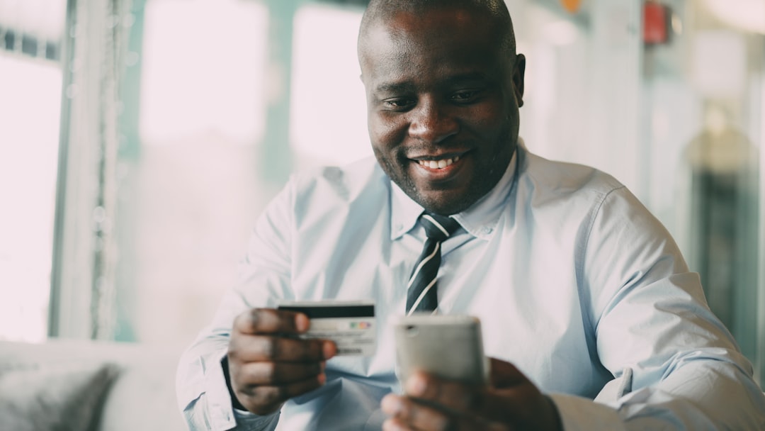 Homem Sorrindo Enquanto Segura Cartao De Credito E Telefone zh6Qq0w_5GU