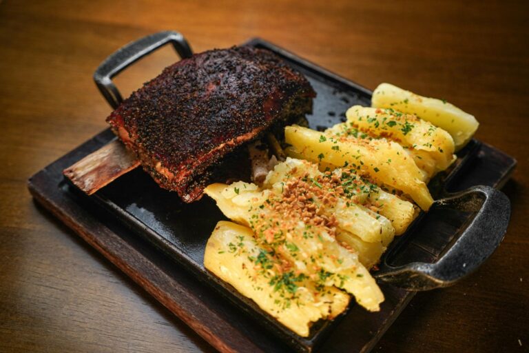 Mouthwatering roasted beef ribs served on a platter with seasoned potatoes and garnished herbs.