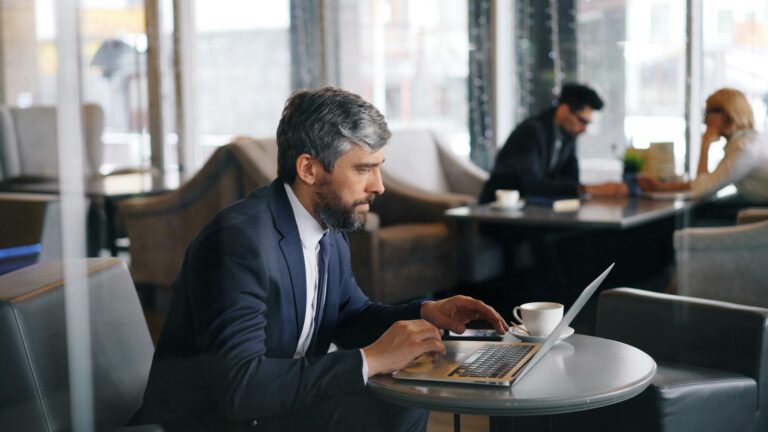 Businessman working on a laptop inside a contemporary café setting, focused and productive.