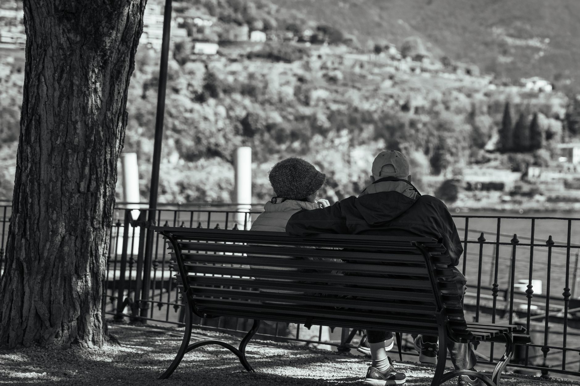 Serene moment of an elderly couple on a bench overlooking Lake Como.