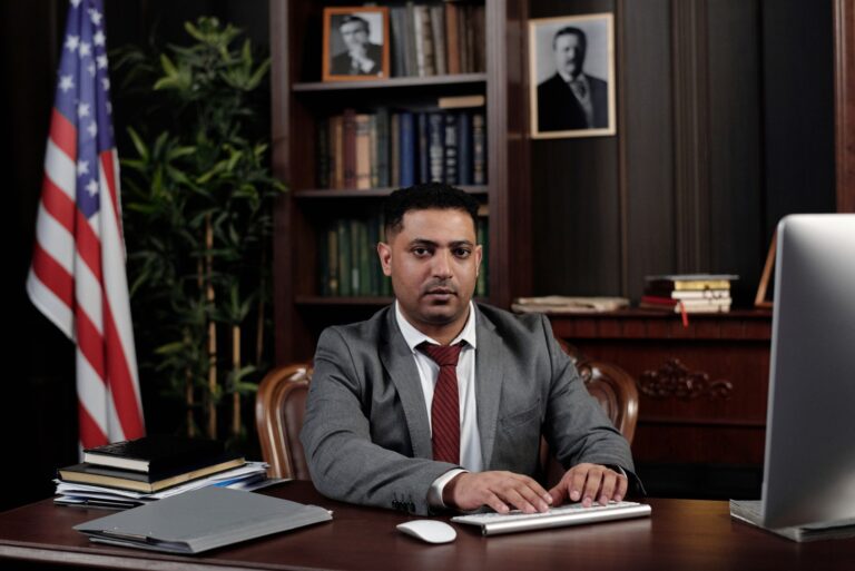 Corporate professional sitting at desk with American flag in office.