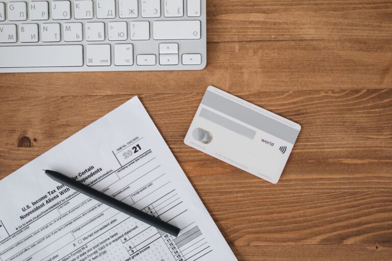 Overhead view of a desk with tax form, pen, keyboard, and contactless card.