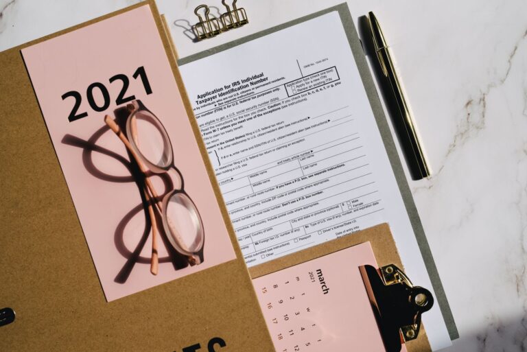 Flat lay of tax forms, calendar, and glasses for 2021 financial planning.
