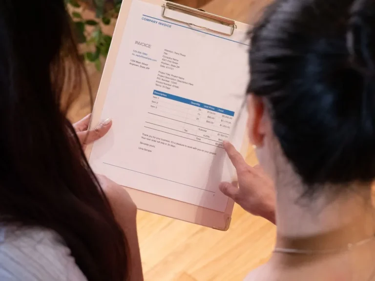 Two individuals reviewing an invoice together in a modern office setting.