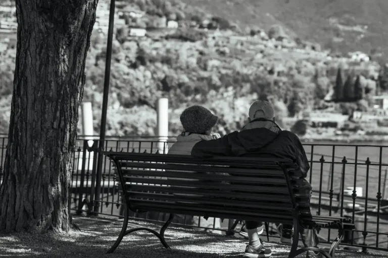 Serene moment of an elderly couple on a bench overlooking Lake Como.