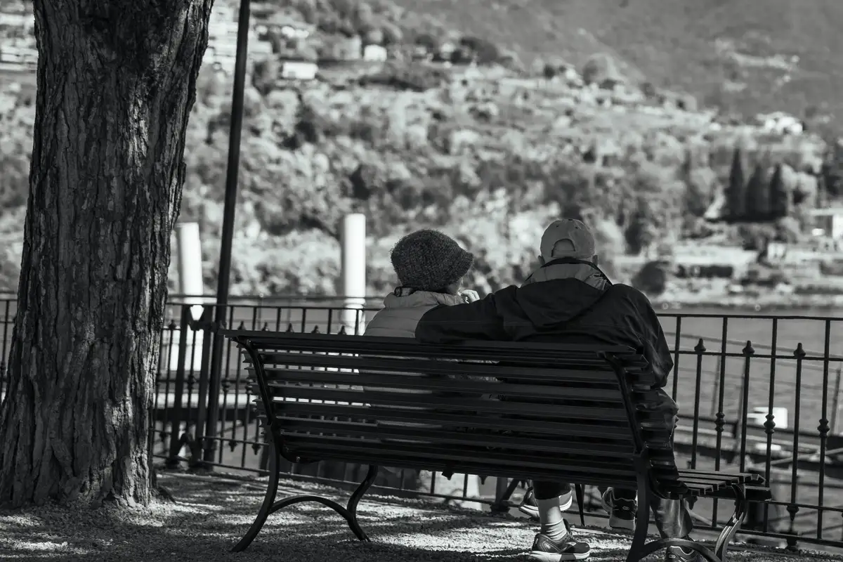 Serene moment of an elderly couple on a bench overlooking Lake Como.