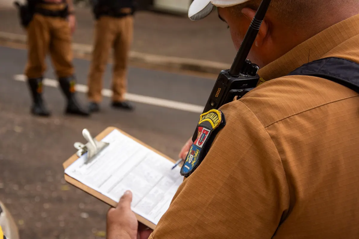 Close-up of a police officer writing on a clipboard outdoors in Londrina, Brazil.